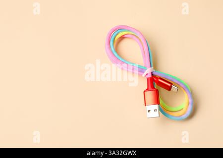 Ein USB-Ladekabel auf beigefarbenem Hintergrund, Draufsicht. Leerzeichen für Text Stockfoto