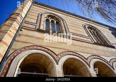 Ein historisches Gebäude in Budapest zeigt einzigartige architektonische Details mit Bogenfenstern und kunstvollen Backsteinmustern. Der klare blaue Himmel wird noch besser Stockfoto