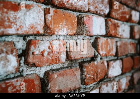 Alte, heruntergekommene Ziegelwand mit grauem Mörtelfleck. Nahaufnahme, keine Leute Stockfoto