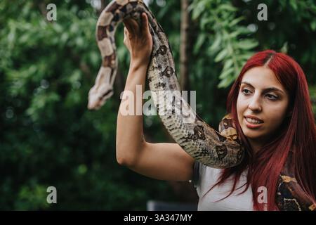 Mädchen mit rotem Haar hält draußen eine große Schlange Stockfoto