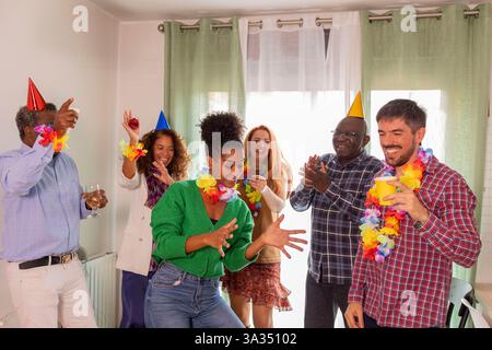 Eine lebhafte Geburtstagsszene mit einer Gruppe von Freunden, die gemeinsam tanzen und feiern. Sie tragen bunte Partyhüte und Leis, die die Freude hervorheben Stockfoto