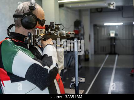 Ein blinder Athlet übt Schießen auf einer olympischen Strecke und zeigt Konzentration und Entschlossenheit. Adaptive Ausrüstung wird verwendet, um Präzision und Enha zu fördern Stockfoto