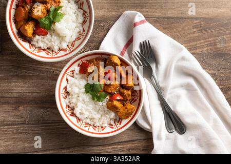 Blick von oben auf zwei Schüsseln ungarischer Schweinegulasch, serviert mit weißem Reis, garniert mit frischer Petersilie auf einem Holztisch. Ein traditionelles Gericht in r Stockfoto