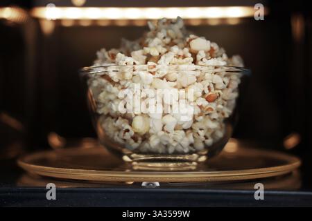 Schüssel mit leckerem Popcorn in der Mikrowelle, Nahaufnahme Stockfoto