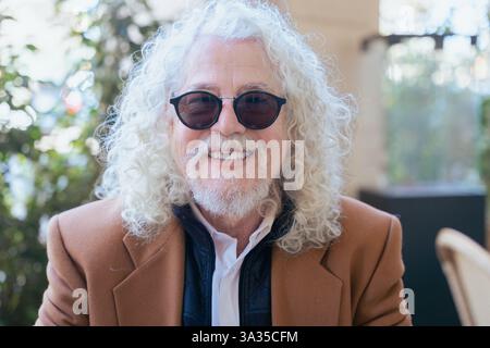 Eleganter Seniorenmann, der in einer urbanen Umgebung im Freien die Kamera anlächelt. Stockfoto
