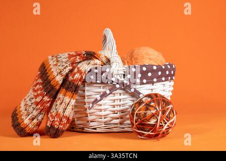 Balls of wool yarn of different colors in a basket, close-up on an orange background. Handmade knitting threads Stockfoto