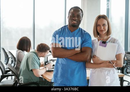 In die Kamera schauen und lächeln. Eine Gruppe von Ärzten ist drinnen zusammen. Stockfoto