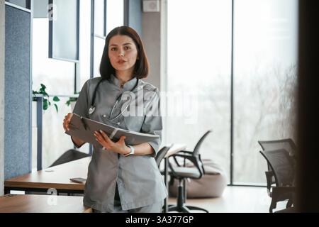Notizblock stehend und in der Hand. Eine Ärztin im Mantel ist drinnen. Stockfoto