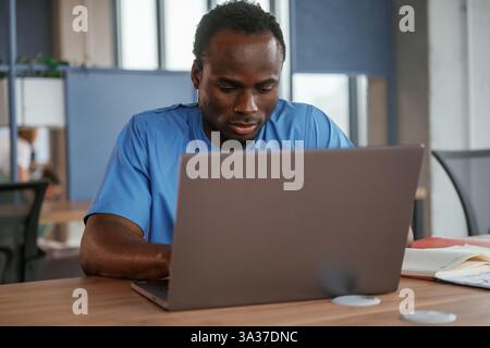 Der Arzt sitzt am Tisch mit Laptop in der Klinik. Stockfoto