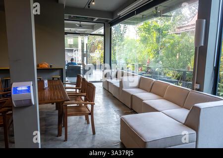 Malaysisches Wohnzimmer im Hotel, Innenraum mit Sitzbereich und Essbereich. Sitzbereich, modulares Ecksofa, Fenster Stockfoto