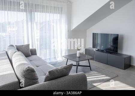 Tivat, Montenegro, 14.03.2025: Gemütliches Wohnzimmer: Sofa, Couchtisch und Fernseher, moderne Einrichtung Stockfoto