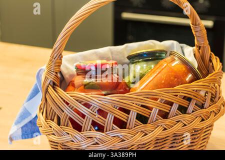 Gläser mit verschiedenen Arten von Gurken und Konfitüren in einem Korb. Essen Stockfoto