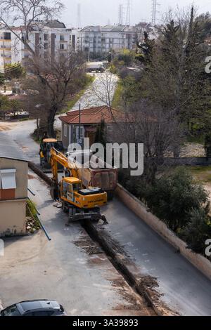 Turkiye, Antalya - 10.03.2025: Schwermaschinenarbeiten auf schmalen Straßen in ruhiger Vorstadt. Die Bauarbeiter arbeiten mit Yello Stockfoto