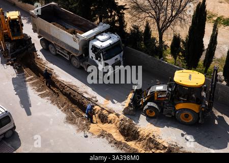 Turkiye, Antalya - 10.03.2025: Schwermaschinenarbeiten auf schmalen Straßen in ruhiger Vorstadt. Die Bauarbeiter arbeiten mit Yello Stockfoto