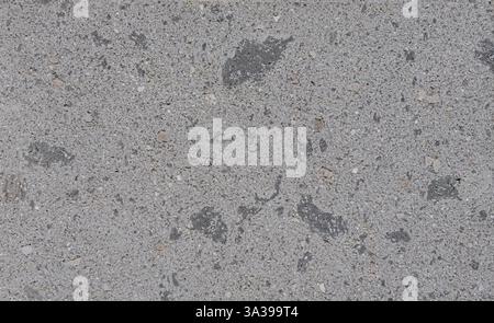 Nahaufnahme einer grauen Betonwand, die feinen Kies und dunkle Flecken freilegt und einen strukturierten Hintergrund schafft, der sich ideal für Bau- und Designprojekte eignet Stockfoto