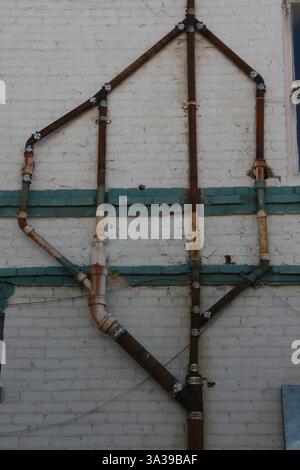 Abflussrohre an der Außenwand eines Ziegelgebäudes bilden ein interessantes Muster. Stockfoto