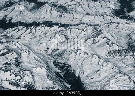 Blick aus der Vogelperspektive auf hohe, schneebedeckte felsige Berge. Alpenlandschaft. Schönheit in der Natur. Unzugängliche Berggipfel. Raues Klima. Sehen Sie sich den an Stockfoto