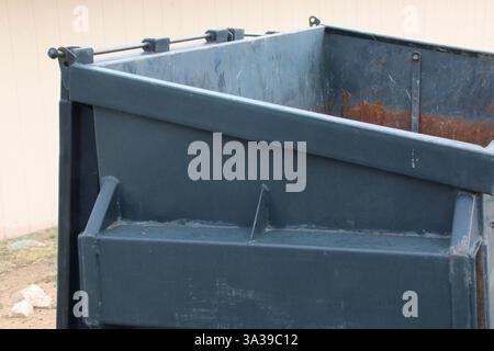 Ein leerer Müllcontainer, der hinter einem Geschäft mit Müll gefüllt wird. Stockfoto