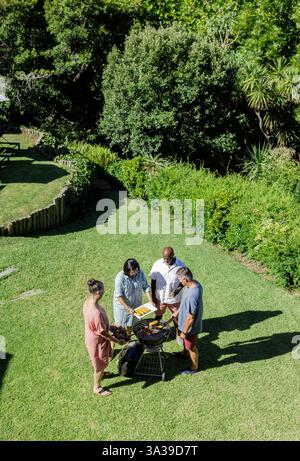Gruppe von Seniorenfreunden, die im Freien Barbecue in üppig grünem Garten genießen, Kopierraum Stockfoto