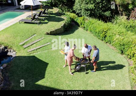 Grillen und Treffen, Seniorenfreunde grillen gemeinsam im sonnigen Hinterhof Stockfoto