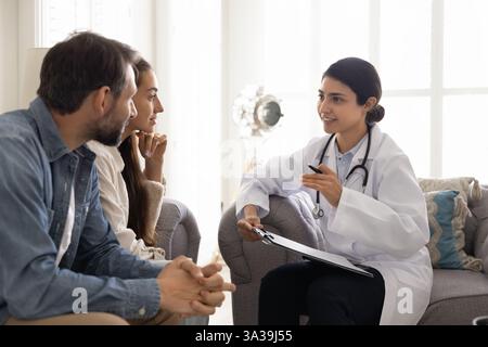 Positive junge indische Ärztin besucht ein Paar zu Hause Stockfoto