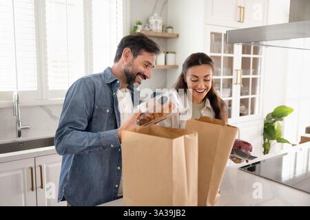 Glückliches Paar, das Papierkuchen mit Bäckerei auspackt Stockfoto
