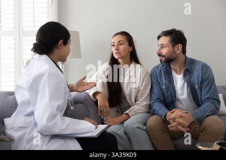 Ernsthaftes junges Paar, das weibliche Ärztin besucht, Beratung über Gesundheitsprobleme Stockfoto