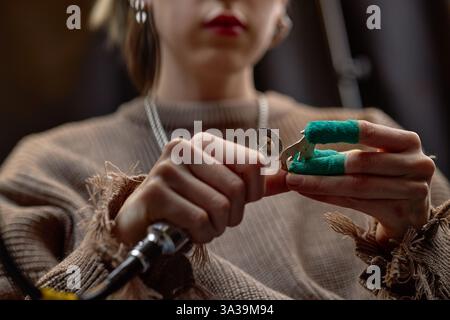 Nahaufnahme von Händen, die Zahnwerkzeuge in der Werkstatt halten, die mit Präzision und Aufmerksamkeit an kleinen Objekten arbeiten und auf Detailarbeit und Handwerkskunst fokussieren Stockfoto