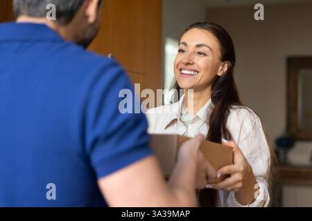 Glückliche junge Adressatin, die erwartetes Paket erhält Stockfoto