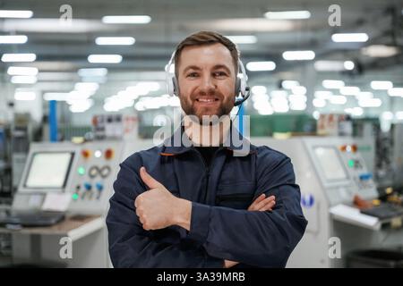 Stehen und lächeln. Fabrikarbeiter ist mit Schutzhelm drinnen. Stockfoto