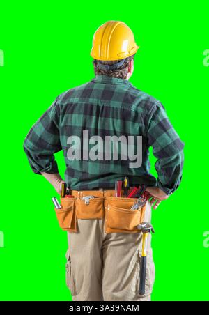 Rückansicht des Bauarbeiters, der einen Werkzeuggürtel trägt und einen Schutzhelm auf dem grünen Bildschirm hält. Stockfoto