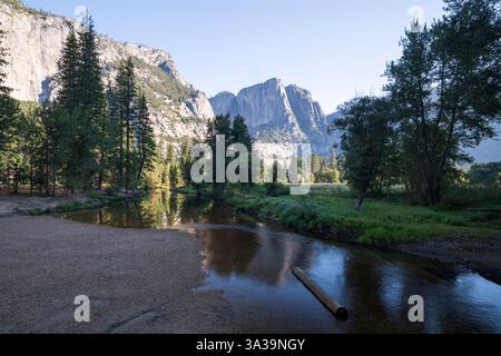 Der Merced River, der an einem ruhigen Sommermorgen durch den Yosemite-Nationalpark fließt. Die majestätischen Granitklippen spiegeln sich im Wasser Stockfoto