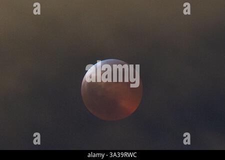 Anchorage, Alaska, USA. März 2025. Anchorage, Alaska – 13. März 20205: Eine totale Mondfinsternis, auch bekannt als „Blutmond“, wird über Anchorage (Alaska) beobachtet, da der Mond aufgrund des Erdschattens einen rötlichen Farbton erhält. Das himmlische Ereignis dauerte mehrere Stunden, wobei die Totalitätsphase ihren Höhepunkt um 22:58 Uhr AKDT erreichte. Die Sonnenfinsternis war teilweise durch Wolkenbedeckung sichtbar, zog aber immer noch Skywatcher und Fotografen in höhere Höhen wie den Flattop Mountain an. Quelle: Hasan Akbas/ZUMA Press Wire/ZUMA Wire/Alamy Live News Stockfoto