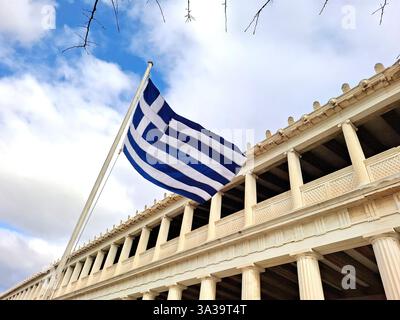 Teilansicht der Stoa von Attalos mit griechischer Nationalflagge, in der Agora von Athen, Griechenland. Es ist ein Denkmal der hellenistischen Ära Stockfoto