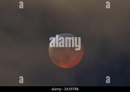 Anchorage, Alaska, USA. März 2025. Anchorage, Alaska – 13. März 20205: Eine totale Mondfinsternis, auch bekannt als „Blutmond“, wird über Anchorage (Alaska) beobachtet, da der Mond aufgrund des Erdschattens einen rötlichen Farbton erhält. Das himmlische Ereignis dauerte mehrere Stunden, wobei die Totalitätsphase ihren Höhepunkt um 22:58 Uhr AKDT erreichte. Die Sonnenfinsternis war teilweise durch Wolkenbedeckung sichtbar, zog aber immer noch Skywatcher und Fotografen in höhere Höhen wie den Flattop Mountain an. Quelle: Hasan Akbas/ZUMA Press Wire/ZUMA Wire/Alamy Live News Stockfoto
