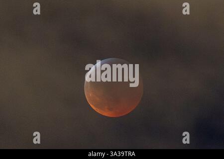 Anchorage, Alaska, USA. März 2025. Anchorage, Alaska – 13. März 20205: Eine totale Mondfinsternis, auch bekannt als „Blutmond“, wird über Anchorage (Alaska) beobachtet, da der Mond aufgrund des Erdschattens einen rötlichen Farbton erhält. Das himmlische Ereignis dauerte mehrere Stunden, wobei die Totalitätsphase ihren Höhepunkt um 22:58 Uhr AKDT erreichte. Die Sonnenfinsternis war teilweise durch Wolkenbedeckung sichtbar, zog aber immer noch Skywatcher und Fotografen in höhere Höhen wie den Flattop Mountain an. Quelle: Hasan Akbas/ZUMA Press Wire/ZUMA Wire/Alamy Live News Stockfoto