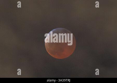 Anchorage, Alaska, USA. März 2025. Anchorage, Alaska – 13. März 20205: Eine totale Mondfinsternis, auch bekannt als „Blutmond“, wird über Anchorage (Alaska) beobachtet, da der Mond aufgrund des Erdschattens einen rötlichen Farbton erhält. Das himmlische Ereignis dauerte mehrere Stunden, wobei die Totalitätsphase ihren Höhepunkt um 22:58 Uhr AKDT erreichte. Die Sonnenfinsternis war teilweise durch Wolkenbedeckung sichtbar, zog aber immer noch Skywatcher und Fotografen in höhere Höhen wie den Flattop Mountain an. Quelle: Hasan Akbas/ZUMA Press Wire/ZUMA Wire/Alamy Live News Stockfoto