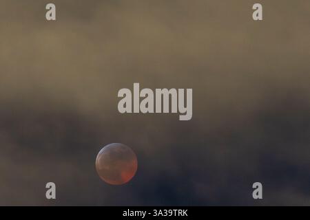 Anchorage, Alaska, USA. März 2025. Anchorage, Alaska – 13. März 20205: Eine totale Mondfinsternis, auch bekannt als „Blutmond“, wird über Anchorage (Alaska) beobachtet, da der Mond aufgrund des Erdschattens einen rötlichen Farbton erhält. Das himmlische Ereignis dauerte mehrere Stunden, wobei die Totalitätsphase ihren Höhepunkt um 22:58 Uhr AKDT erreichte. Die Sonnenfinsternis war teilweise durch Wolkenbedeckung sichtbar, zog aber immer noch Skywatcher und Fotografen in höhere Höhen wie den Flattop Mountain an. Quelle: Hasan Akbas/ZUMA Press Wire/ZUMA Wire/Alamy Live News Stockfoto