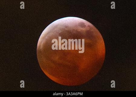 Blood Moon Eclipse in Alaska Anchorage, Alaska 13. März 20205: Eine faszinierende totale Mondfinsternis, auch bekannt als Blood Moon, wirft ein tiefrotes Leuchten über den Nachthimmel in Anchorage, Alaska. Während der Schatten der Erde den Mond vollständig umhüllt, fesselt das seltene himmlische Ereignis Sternenbeobachter und Fotografen gleichermaßen. Trotz teilweiser Wolkenbedeckung bleibt das Phänomen von erhöhten Orten wie Anchorage City aus sichtbar und bietet einen atemberaubenden Blick auf dieses astronomische Spektakel. Die Sonnenfinsternis erreichte ihren Höhepunkt um 22:58 Uhr AKDT und zog die Aufmerksamkeit der Skywatcher in der Region auf sich. Copyright: XHASANxAKBASx Stockfoto