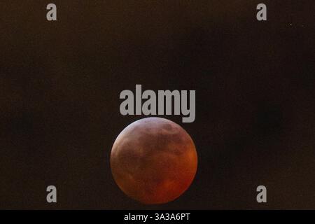Blood Moon Eclipse in Alaska Anchorage, Alaska 13. März 20205: Eine faszinierende totale Mondfinsternis, auch bekannt als Blood Moon, wirft ein tiefrotes Leuchten über den Nachthimmel in Anchorage, Alaska. Während der Schatten der Erde den Mond vollständig umhüllt, fesselt das seltene himmlische Ereignis Sternenbeobachter und Fotografen gleichermaßen. Trotz teilweiser Wolkenbedeckung bleibt das Phänomen von erhöhten Orten wie Anchorage City aus sichtbar und bietet einen atemberaubenden Blick auf dieses astronomische Spektakel. Die Sonnenfinsternis erreichte ihren Höhepunkt um 22:58 Uhr AKDT und zog die Aufmerksamkeit der Skywatcher in der Region auf sich. Copyright: XHASANxAKBASx Stockfoto