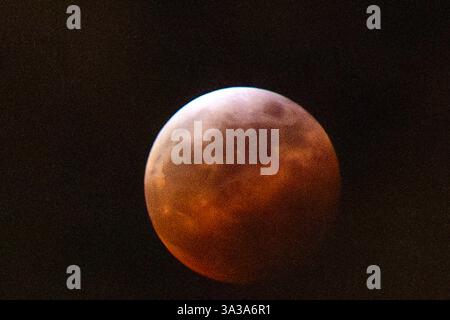 Blood Moon Eclipse in Alaska Anchorage, Alaska 13. März 20205: Eine faszinierende totale Mondfinsternis, auch bekannt als Blood Moon, wirft ein tiefrotes Leuchten über den Nachthimmel in Anchorage, Alaska. Während der Schatten der Erde den Mond vollständig umhüllt, fesselt das seltene himmlische Ereignis Sternenbeobachter und Fotografen gleichermaßen. Trotz teilweiser Wolkenbedeckung bleibt das Phänomen von erhöhten Orten wie Anchorage City aus sichtbar und bietet einen atemberaubenden Blick auf dieses astronomische Spektakel. Die Sonnenfinsternis erreichte ihren Höhepunkt um 22:58 Uhr AKDT und zog die Aufmerksamkeit der Skywatcher in der Region auf sich. Copyright: XHASANxAKBASx Stockfoto