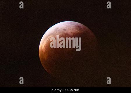 Blood Moon Eclipse in Alaska Anchorage, Alaska 13. März 20205: Eine faszinierende totale Mondfinsternis, auch bekannt als Blood Moon, wirft ein tiefrotes Leuchten über den Nachthimmel in Anchorage, Alaska. Während der Schatten der Erde den Mond vollständig umhüllt, fesselt das seltene himmlische Ereignis Sternenbeobachter und Fotografen gleichermaßen. Trotz teilweiser Wolkenbedeckung bleibt das Phänomen von erhöhten Orten wie Anchorage City aus sichtbar und bietet einen atemberaubenden Blick auf dieses astronomische Spektakel. Die Sonnenfinsternis erreichte ihren Höhepunkt um 22:58 Uhr AKDT und zog die Aufmerksamkeit der Skywatcher in der Region auf sich. Copyright: XHASANxAKBASx Stockfoto