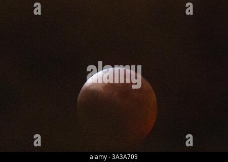Blood Moon Eclipse in Alaska Anchorage, Alaska 13. März 20205: Eine faszinierende totale Mondfinsternis, auch bekannt als Blood Moon, wirft ein tiefrotes Leuchten über den Nachthimmel in Anchorage, Alaska. Während der Schatten der Erde den Mond vollständig umhüllt, fesselt das seltene himmlische Ereignis Sternenbeobachter und Fotografen gleichermaßen. Trotz teilweiser Wolkenbedeckung bleibt das Phänomen von erhöhten Orten wie Anchorage City aus sichtbar und bietet einen atemberaubenden Blick auf dieses astronomische Spektakel. Die Sonnenfinsternis erreichte ihren Höhepunkt um 22:58 Uhr AKDT und zog die Aufmerksamkeit der Skywatcher in der Region auf sich. Copyright: XHASANxAKBASx Stockfoto