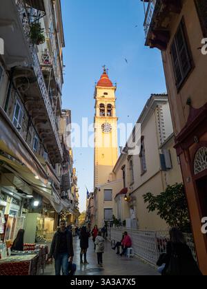 Der Uhrenturm inmitten der belebten Marktstraße ist im Sonnenlicht getaucht, vor dem klaren blauen Himmel, der unter ihnen herrscht. Stockfoto