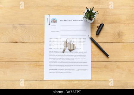 Leeres Haus Mietvertrag mit Schlüssel und Pflanze auf hölzernem Hintergrund Stockfoto
