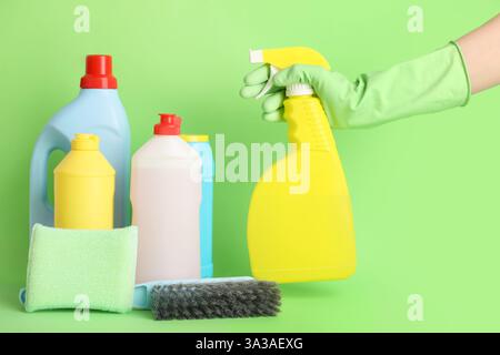 Hand des Hausmeisters und Reinigungsmittel auf grünem Hintergrund Stockfoto
