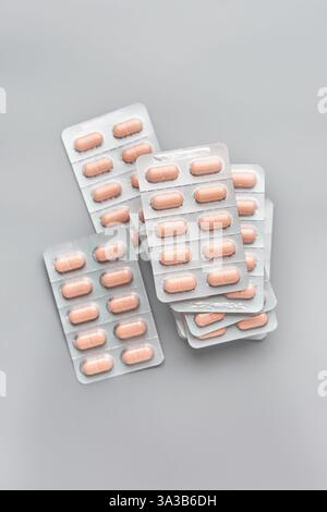 Gestapelte hellbraune Farbtabletten oder Pillen in Silberfolie Rückseite Blisterpackungen isolierter grauer Hintergrund, Pakete von Medikamenten, weiche Fokus Stockfoto