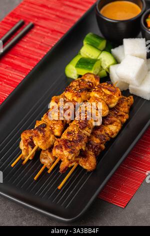 Gegrillte Hähnchenspieße mit Erdnusssauce, Reiskuchen und Gemüse Stockfoto