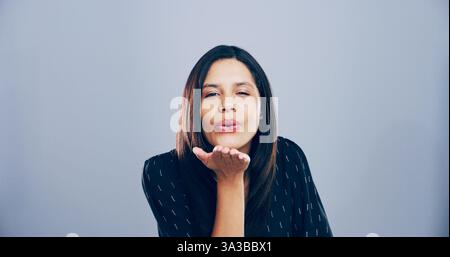 Porträt, Frau und Blowing Kuss im Studio, Flirten und Gesten für Romantik für Valentinstag oder Raum. Blauer Hintergrund, Modell und Person mit Stockfoto