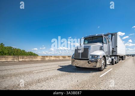 Industrieller flacher, grauer Big Rig-Sattelauflieger mit verlängerter Kabine für Lkw-Fahrer, der Ladung in Kühlschrankauflieger transportieren kann Stockfoto
